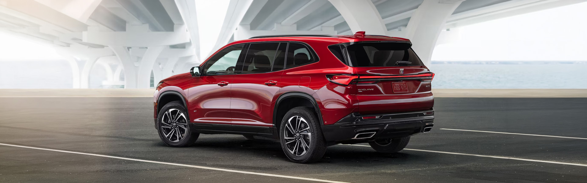 2026 Buick Enclave SUV parked under a bridge, showcasing its sleek red exterior and modern design.